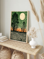 Linocut style moonlit field print with dark green sky, orange horizon, silhouetted trees, and, in an alternate framed mockup
