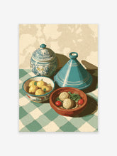 Moroccan kitchen art print with a blue tagine, lidded pot, lemons, and food on a green checkered tablecloth.