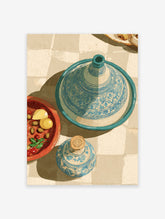 Moroccan Wall Art print of a blue patterned tagine, olives, lemon, and a decorative bottle on a tiled surface.