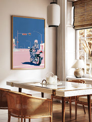 Illustrative motorcycle wall art with rider in patterned suit and pink helmet at city intersection, in a styled room mockup