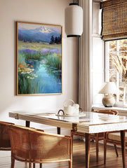 Impressionistic painting of a winding stream through a wildflower meadow towards a snow-capped, in a styled room mockup
