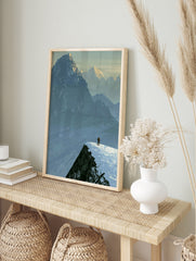 Illustrative mountain landscape art print showing a lone skier on a snowy ridge against a, in an alternate framed mockup