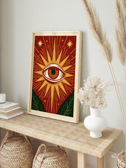 Mystical eye illustration with sunburst rays, stars, and green leaves on a red background, in an alternate framed mockup