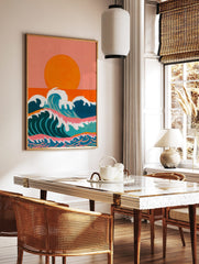 Illustrative ocean waves with white foam under a large orange sun and peachy-pink sky, in a styled room mockup
