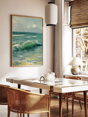 Close-up painting of green and blue ocean waves crashing onto a sandy beach under a cloudy sky, in a styled room mockup