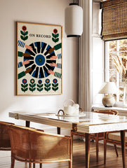 On Record wall art print showing a vinyl record held by multiple hands with floral motifs in a, in a styled room mockup