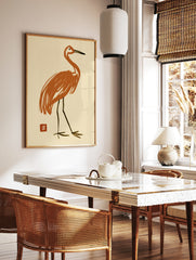 Stylized orange crane bird illustration with Japanese-style red seal on cream background, in a styled room mockup