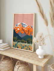Illustrative landscape art print of orange snow-capped mountains, teal hills, and wildflower, in an alternate framed mockup
