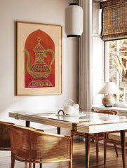 Ornate gold-green coffee pot with magenta patterns against a reddish-orange arch on a beige, in a styled room mockup