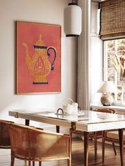 Ornate golden teapot with dark blue accents and intricate patterns on a coral background, showing a, in a styled room mockup