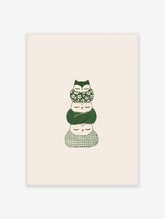 Stack of three sleeping owls in green floral, solid, and checked wraps on beige background
