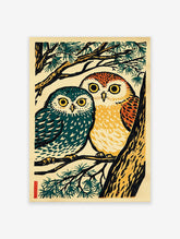 Japanese woodcut style print of two owls, one teal and one orange, perched on a pine tree branch with green needles.