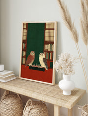 Illustrative print of a tawny owl and a white owl playing chess on a red table, flanked by, in an alternate framed mockup