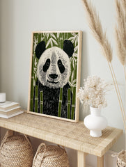 Illustrative linocut style panda bear art print in black, white, and green bamboo forest, in an alternate framed mockup