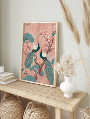 Two teal peacocks on a brown branch with pink cherry blossoms and teal foliage on a pink, in an alternate framed mockup