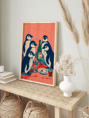 Illustrative print of five navy and white penguins at a table with a green bottle and cups on, in an alternate framed mockup