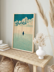 Illustrative print of a penguin walking on snow towards distant mountains under a blue sky, in an alternate framed mockup