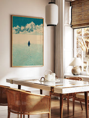 Illustrative print of a penguin walking on snow towards distant mountains under a blue sky, leaving, in a styled room mockup