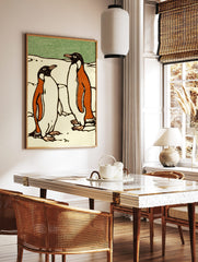 Illustrative print of two penguins in black, orange, and white on snow with a green background, in a styled room mockup