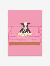 Illustrative art print of a black and white cow sitting on a pink couch, set against a solid pink background.