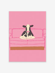 Illustrative art print of a black and white cow sitting on a pink couch, set against a solid pink background.
