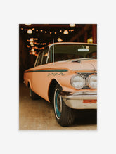 Peach pink vintage car poster with chrome bumper, blue wheels, and warm string lights in background