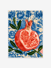 Halved pomegranate with red seeds and green leaves against a blue floral tile pattern