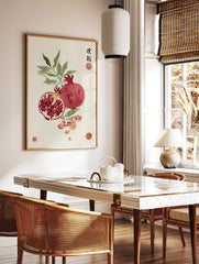 Pomegranate watercolour illustration with whole and cut fruit, green leaves, scattered petals, and, in a styled room mockup