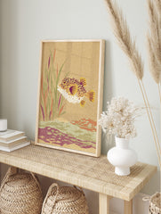 Textured illustration of a spiky puffer fish swimming among aquatic plants and a seabed in, in an alternate framed mockup