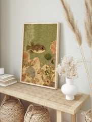 Spotted pufferfish swimming right in green water with white and brown coral, plants, and, in an alternate framed mockup