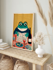 Illustrative art print of a frog in glasses reading a newspaper at a dining table with wine, in an alternate framed mockup