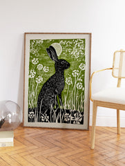Black rabbit linocut print in a green field with white flowers and a moon, illustrative wall art. - Image 2