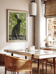 Black rabbit linocut print in a green field with white flowers and a moon, illustrative wall art. - Image 3