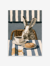 Watercolor illustration of a rabbit with a coffee cup and doughnut on a blue and white striped table surface