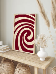 Abstract red and cream spiral wall art with bold, swirling lines and a hypnotic composition, in an alternate framed mockup