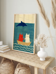 Red and white cat illustration with a blue dolphin in a boat on a blue sea, in an alternate framed mockup