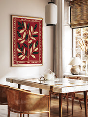 Symmetrical botanical leaf illustration in cream on a deep red background with a decorative dotted, in a styled room mockup