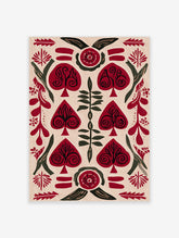 Red and green folk art botanical print with spade-shaped leaves and swirling motifs on cream background