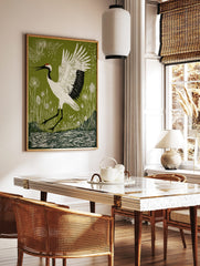 Linocut style print of a white red-crowned crane with black markings and red crown, wings spread, in a styled room mockup