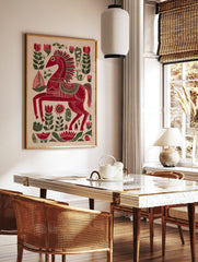 Red folk art horse print with intricate white and green patterns, surrounded by red and green, in a styled room mockup