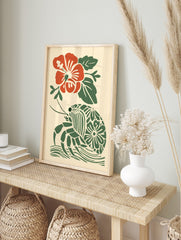 Red hibiscus flower and green hermit crab with patterned shell in a tropical block print style, in an alternate framed mockup