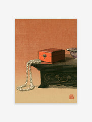 Still life art print of a red lacquer box and pearl necklace on a wooden table with a red seal stamp