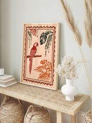 Red parrot illustration perched on a branch with tropical monstera and palm leaves, in an alternate framed mockup