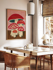 Illustrative red spotted mushroom wall art with white stems and pink background, in an alternate framed mockup