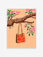 Red and yellow tote bag hanging from a tree branch with pink cherry blossom flowers on a peach background
