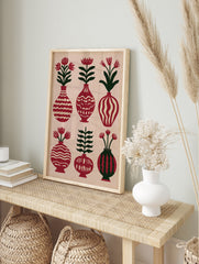 A folk art botanical poster showing six vases with flowers and leaves in red and green on a, in an alternate framed mockup