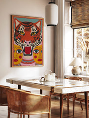 Stylised roaring tiger face with two yellow human faces below, in a vibrant folk art inspired print, in a styled room mockup