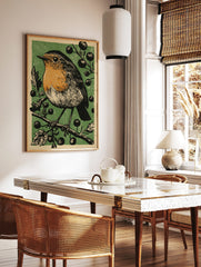 Illustrative print of a robin bird with an orange breast perched on a branch with dark berries, in a styled room mockup
