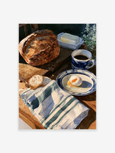 Still life painting of bread, a soft-boiled egg in a blue bowl, coffee, and a green striped towel on a wooden table