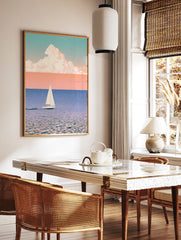 Minimalist sailboat wall art with soft pastel sky, blue water, and large cloud illustration on, in a styled room mockup